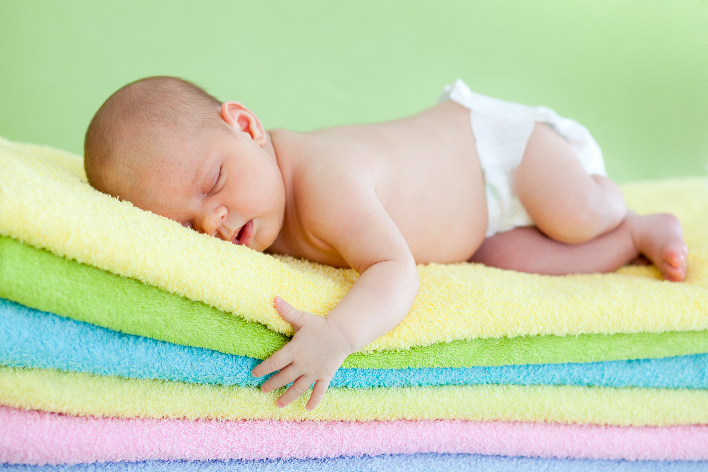 newborn baby girl weared cap sleeping on colourful towels