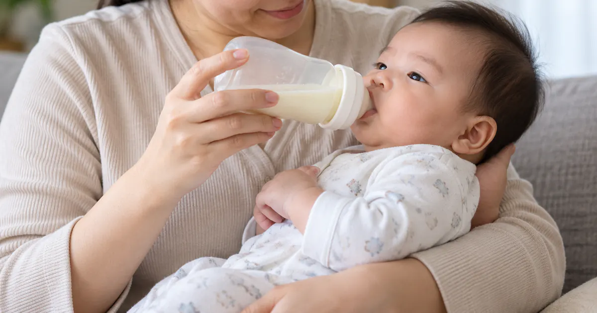 Cha mẹ giữ bình gần nằm ngang để điều chỉnh tốc độ bú của trẻ